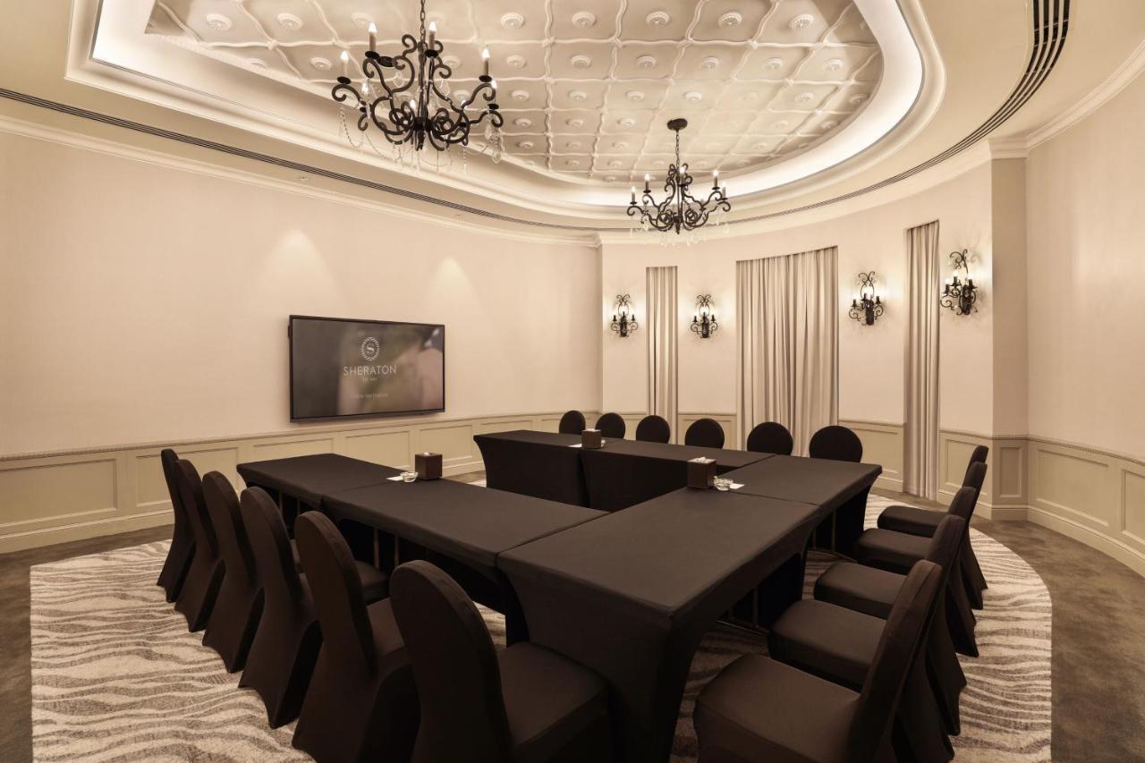Sheraton Abu Dhabi Hotel&Resort Esterno foto The photo shows a large, elegantly arranged conference room. In the center, there is a long rectangular table covered with a black tablecloth. Surrounding the table are several black upholstered chairs. The room features a sophisticated design with a