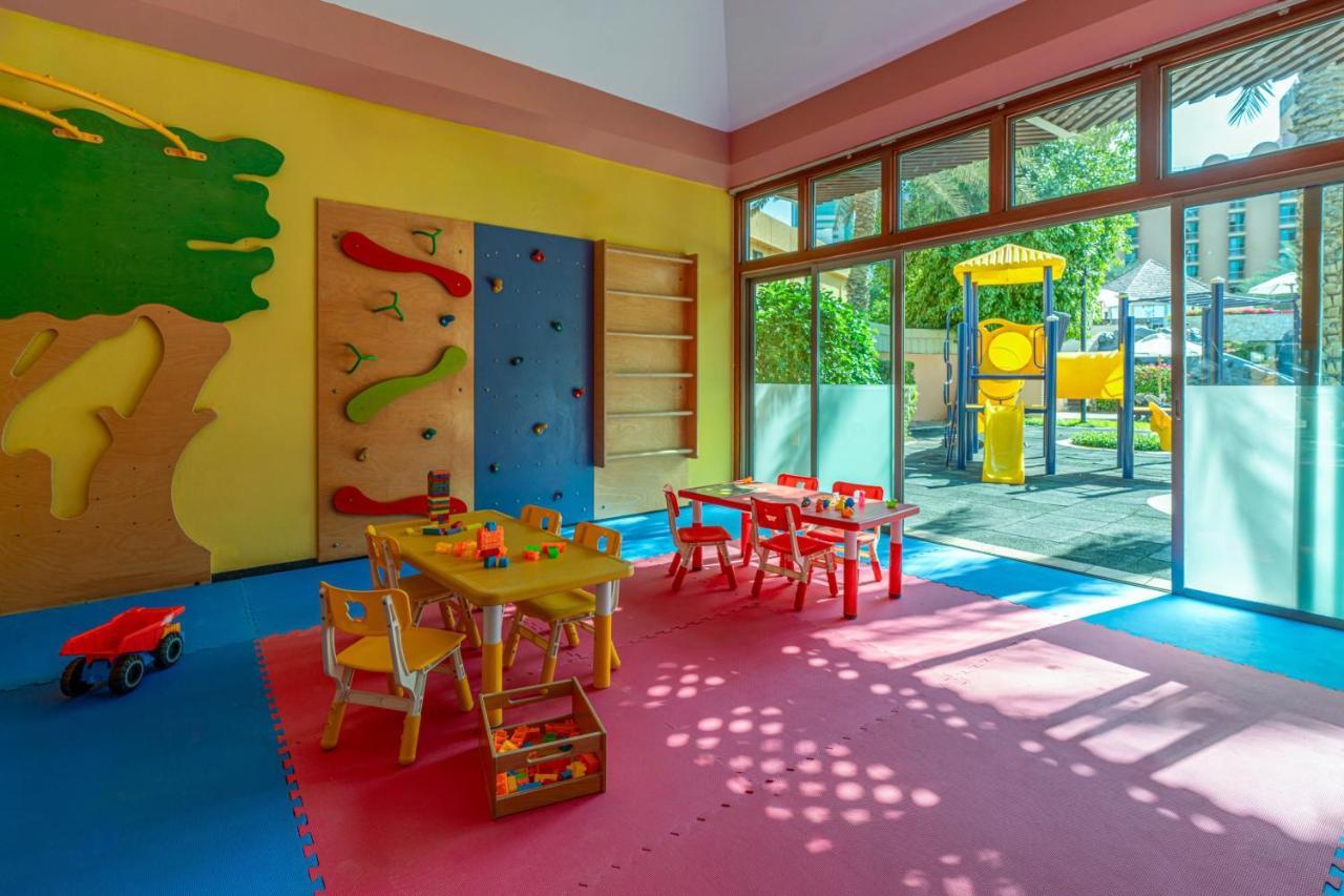 Sheraton Abu Dhabi Hotel&Resort Esterno foto The photo shows a colorful children's playroom. The walls are painted in bright yellow and pink hues, creating a cheerful atmosphere. On one side, there is a climbing wall with various colorful grips for children to climb. The floor is covered in sof