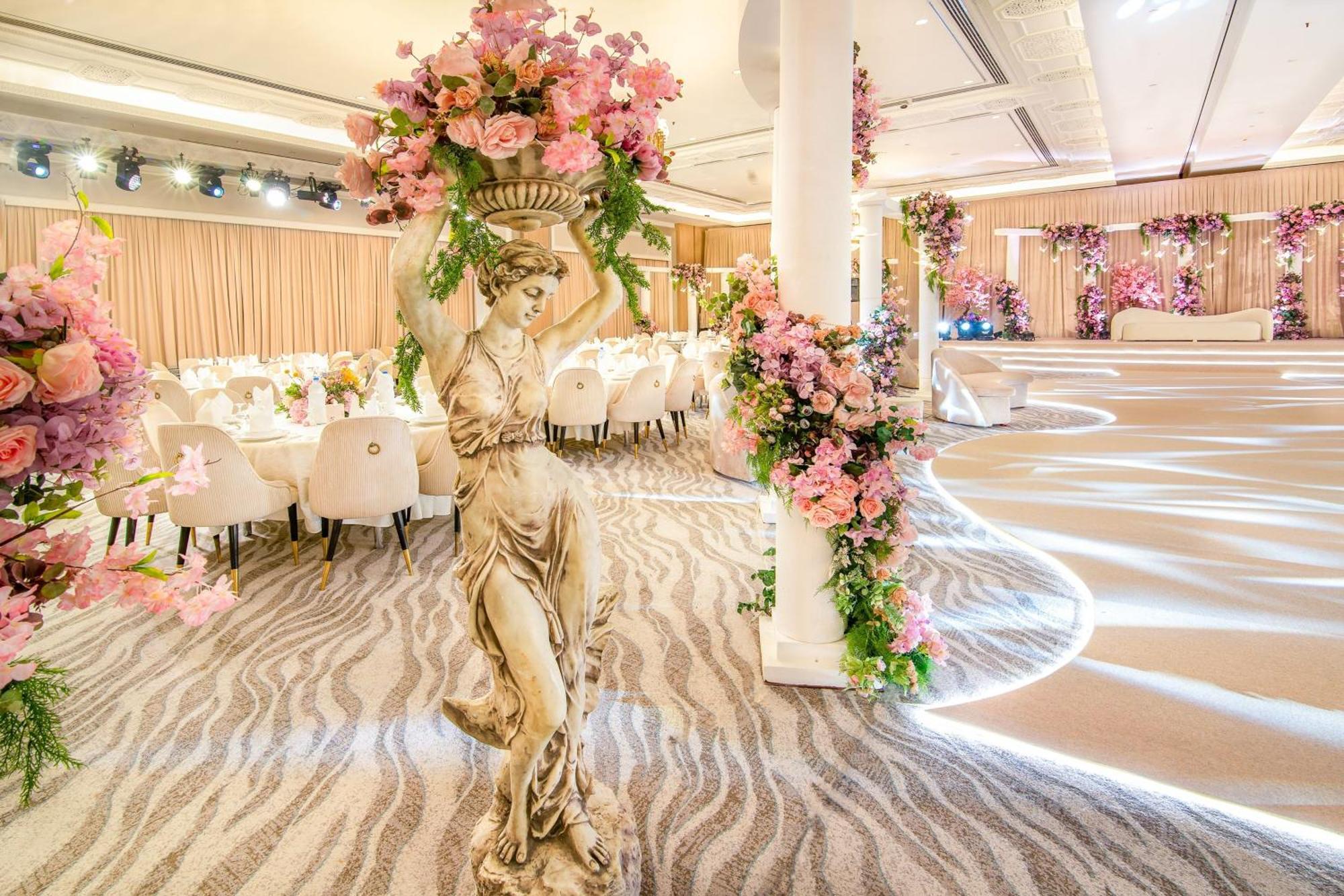 Sheraton Abu Dhabi Hotel&Resort Esterno foto The photo shows an elegantly decorated interior space, likely set up for an event such as a wedding or formal gathering. Decorative elements include:

- A large statue or column featuring a figure holding a floral arrangement, adorned with pink flowe