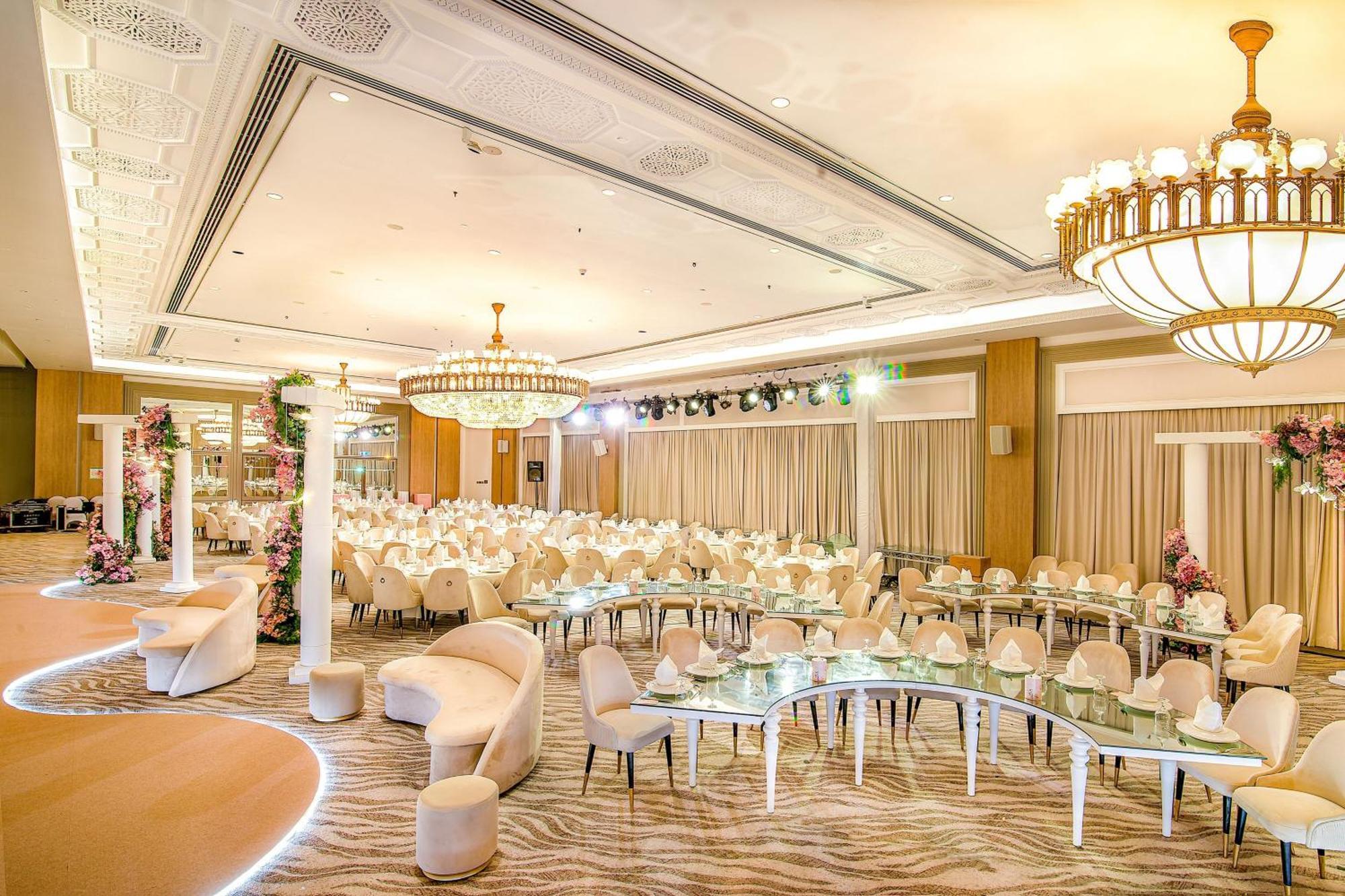 Sheraton Abu Dhabi Hotel&Resort Esterno foto The photo shows an elegant banquet hall or event space. The room features a sophisticated decor with a large chandelier hanging from the ceiling. There are numerous tables arranged in a circular pattern, each set with white chairs, suggesting it is p
