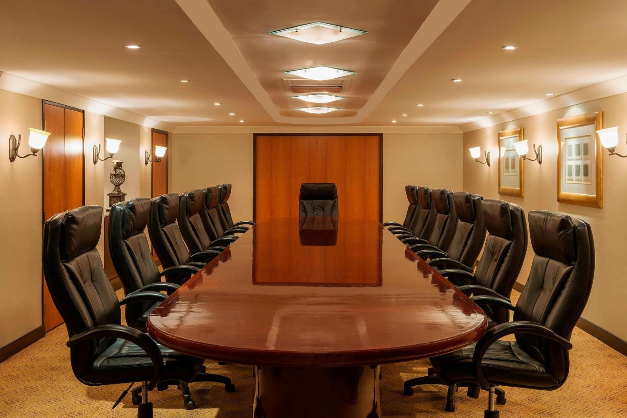 Sheraton Abu Dhabi Hotel&Resort Esterno foto The photo displays a large, elegant boardroom. In the center, there is a long, polished wooden table surrounded by black leather executive chairs. The room features soft lighting, with ceiling lights and wall sconces providing illumination. At the fa