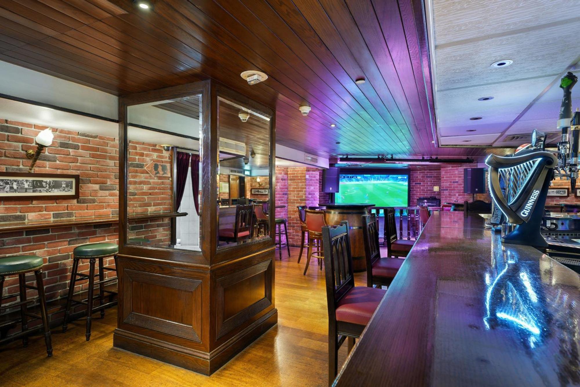Sheraton Abu Dhabi Hotel&Resort Esterno foto The photo shows the interior of a bar or pub. It features wooden paneling on the ceiling and walls, giving a warm and inviting atmosphere. There are several bar stools and tables arranged neatly, with a long wooden bar counter in the foreground. At t