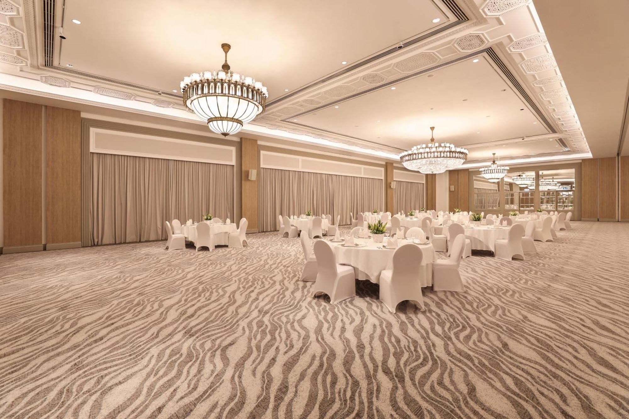 Sheraton Abu Dhabi Hotel&Resort Esterno foto The photo shows a large, elegant banquet hall or event space. It features a stylish carpet with a patterned design that resembles soft stripes. The room is illuminated by several ornate chandeliers hanging from the ceiling, adding a luxurious touch. 