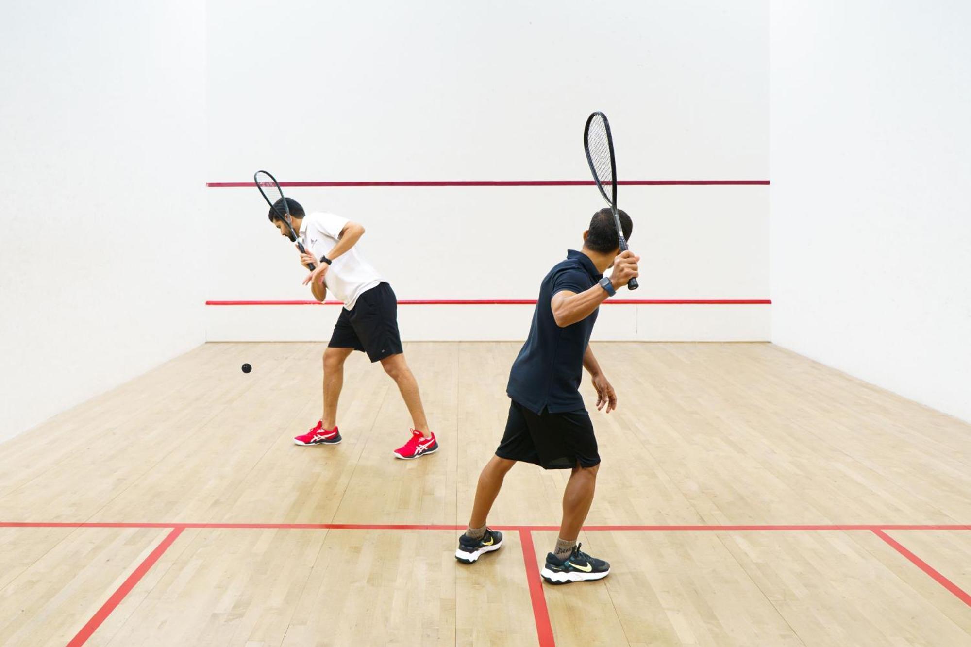 Sheraton Abu Dhabi Hotel&Resort Esterno foto The photo shows two individuals playing squash in a squash court. Each player is holding a racket and appears to be in action, with one player hitting the ball and the other preparing to return it. The court features a wooden floor and white walls, w